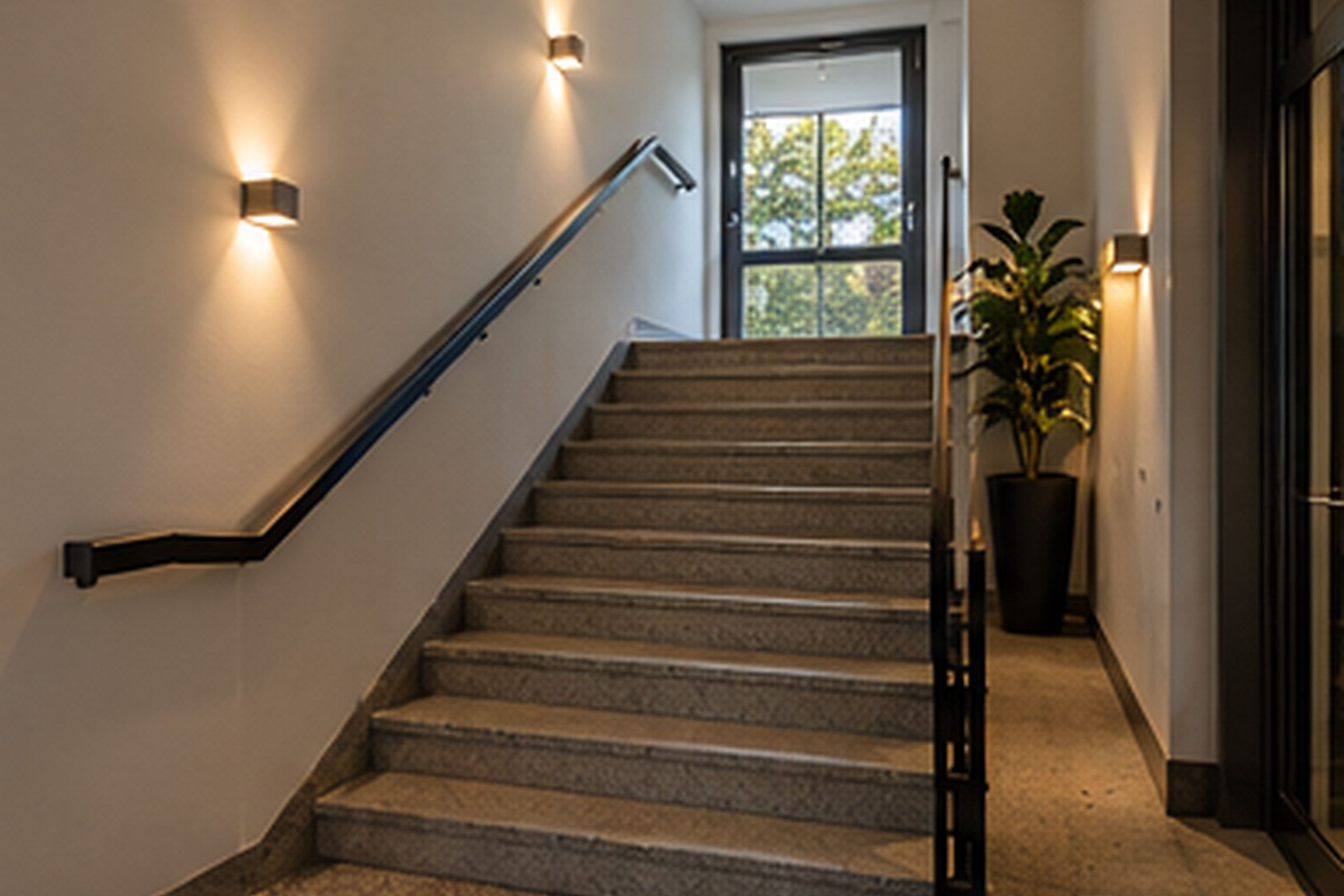 Frisch renoviertes Treppenhaus mit hellen Wänden und dunklem Handlauf